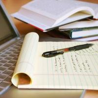 A filled in notepad on a laptop with open textbooks in the background